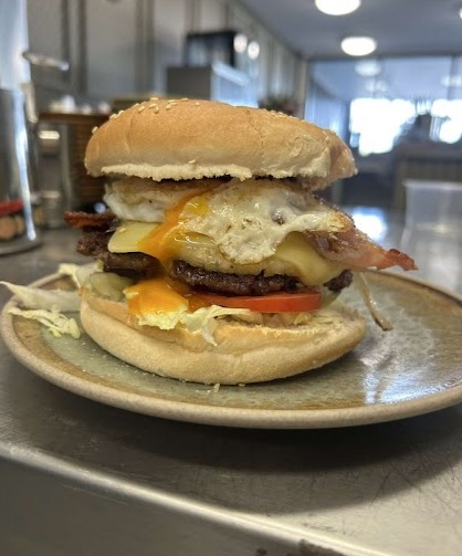 A double burger with egg, bacon, cheese and tomato
